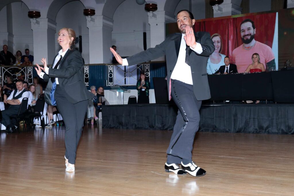 Couple dressed in suits dancing in the ballroom at the Winter Gardens to raise money for Weston Hospicecare at a previous Strictly Fun Dancing Grand Finale.