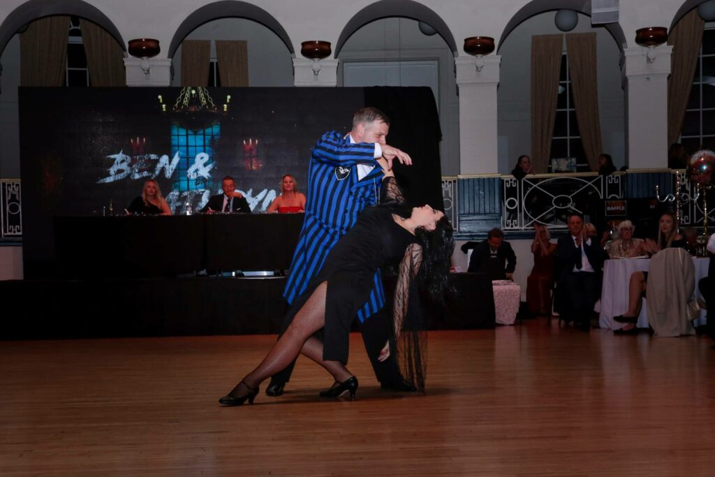 Couple performing in a blue suit and black costume in the ballroom at the Winter Gardens to raise money for Weston Hospicecare at a previous Strictly Fun Dancing Grand Finale.