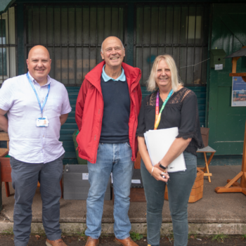 A photo of a member of the Men in Sheds group with Dave from Weston Hospicecare and Debbie from North Somerset council outside the Men in Sheds hut in Clarence Park.