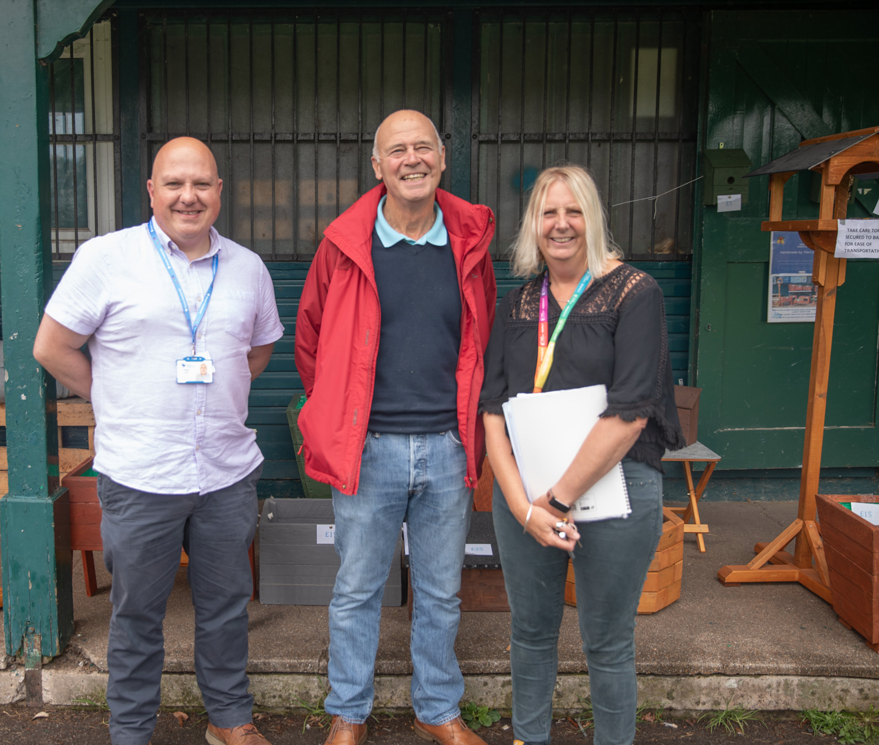 A photo of a member of the Men in Sheds group with Dave from Weston Hospicecare and Debbie from North Somerset council outside the Men in Sheds hut in Clarence Park.